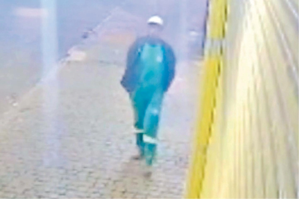 Serial Killer de Rio Verde (GO) com uniforme de limpeza urbana caminha na calçada; imagem de câmera de segurança, desfocada.