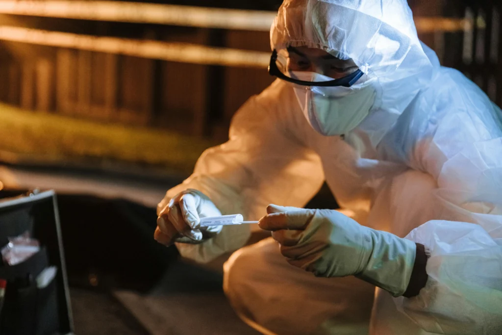 Perito coleta evidências forenses em cena de crime com roupas e luvas de segurança. Cena de true crime.