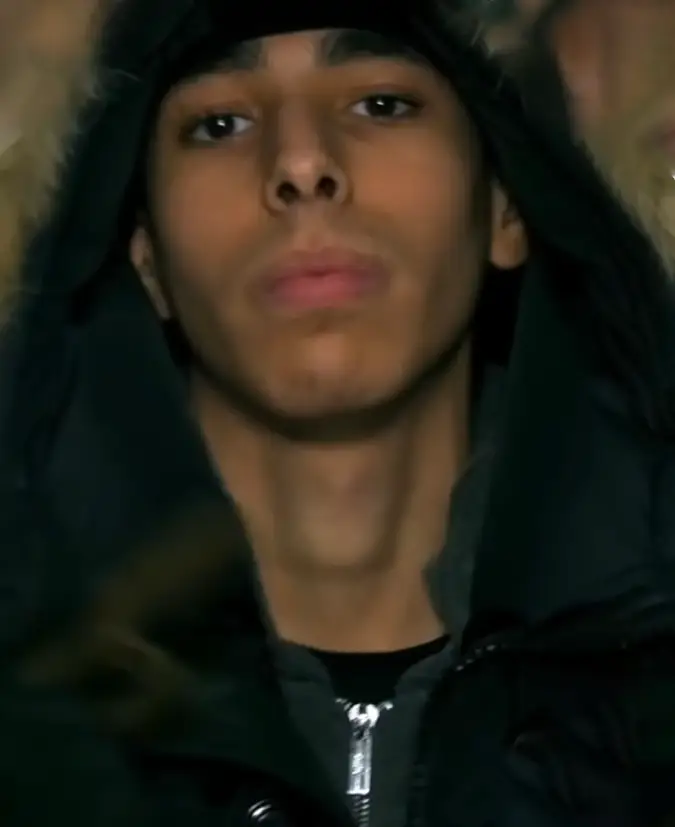 Close-up do rosto do rapper sueco Hamko, usando um casaco de inverno com capuz, em uma imagem que reflete o universo sombrio do true crime que marcou sua vida.